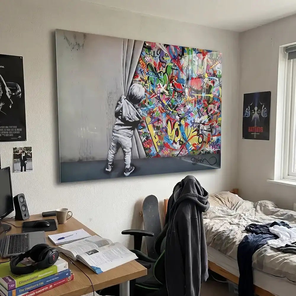 Un grand tirage sur toile présentant une représentation en noir et blanc d'un enfant tirant un rideau pour révéler un art graffiti vibrant et coloré derrière lui.