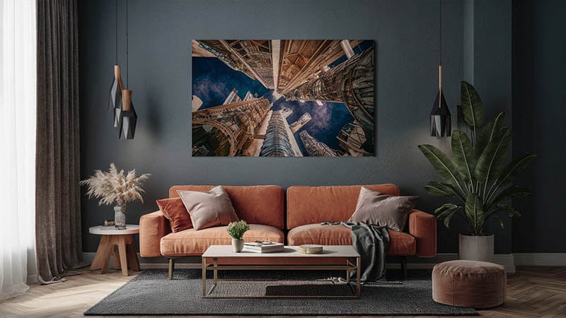 canapé en velours orange avec coussins assortis et une couverture grise drapée sur un accoudoir, illustrant la décoration murale avec la photographie artistique adaptée