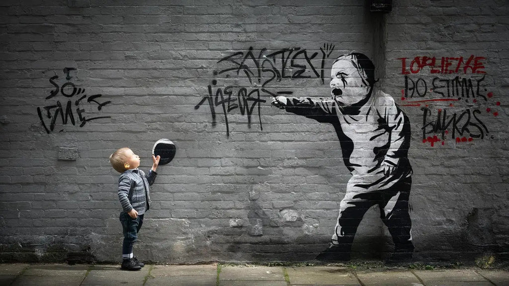 une maison décorée avec un street art unique montrant une fresque murale en pochoir noir et blanc d’un enfant pointant un autre sur un mur en briques grises.