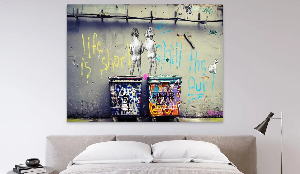 canvas graffiti style représentant deux enfants nus devant des poubelles colorées taguées avec le texte life is short chill the out en jaune et bleu pour incorporer lart urbain dans la décoration de votre chambre