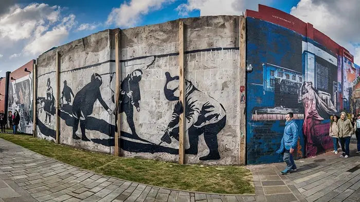 un long mur en béton usé décoré d’une peinture murale pochoir noir et blanc de banksy pour une décoration moderne et inspirante