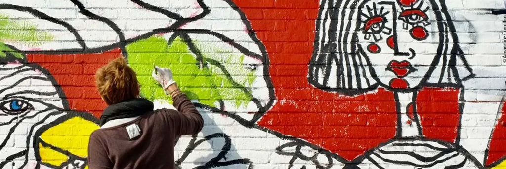 une fresque murale urbaine vibrante représentant une femme stylisée avec des lèvres rouges audacieuses et des yeux en contours noirs sur un mur en briques blanches pour des idées cadeaux originales autour de lart urbain et du graffiti