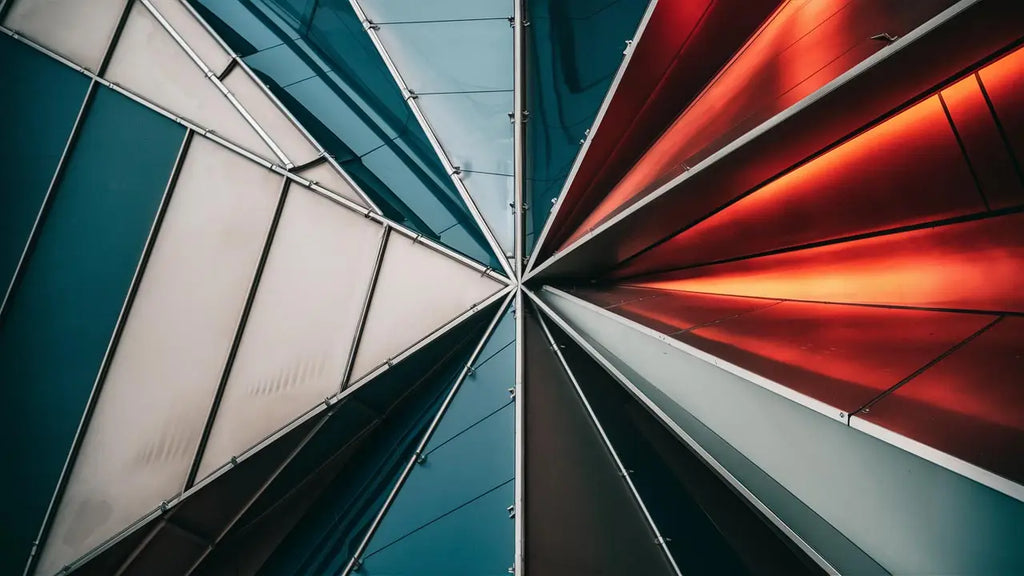 plafond en verre géométrique avec panneaux teal blanc et rouge encadrés par des poutres métalliques dans un article sur les tendances de couleurs et motifs en décoration contemporaine