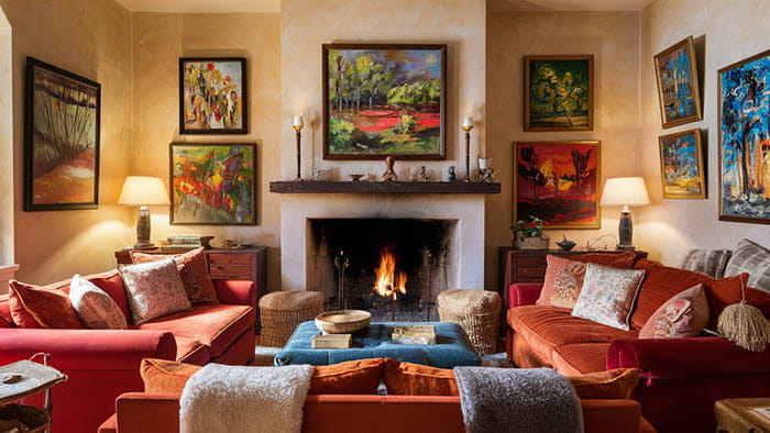 le salon chaleureux présente une cheminée invitante avec un manteau en pierre blanche et un feu actif comme idée simple pour embellir vos murs