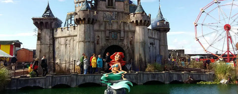 une statue de sirène verte et bleu sarcelle aux cheveux flottants est installée devant lentrée en pierre dun château dans larticle banksy dismaland